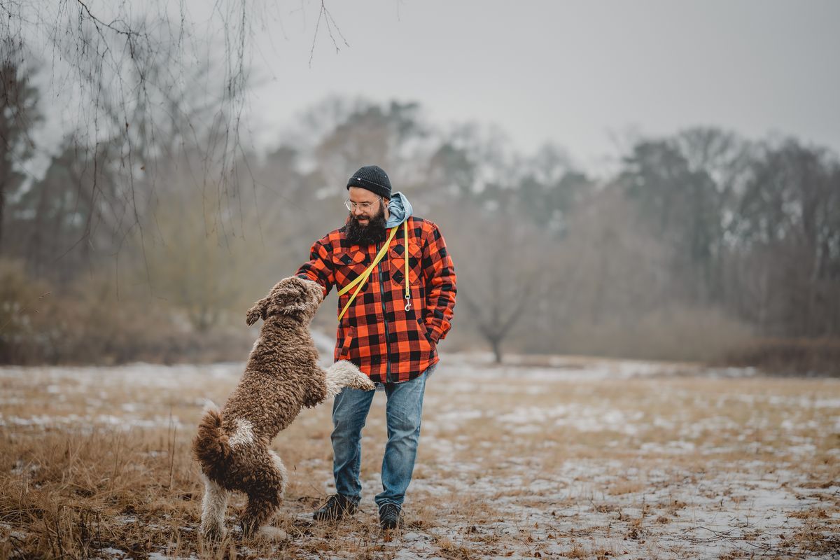 Mann spielt mit Hund im Feld