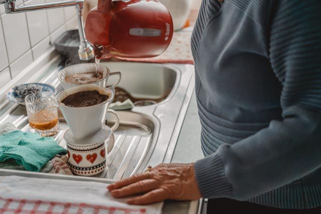 Frau gießt Kaffee in der Küche